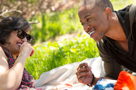 Young couple reclining on picnic blanket in parkの写真素材