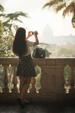 Woman taking pictures with mobile phone, Pincio Gardens, Villa Borghese, Romeの写真素材