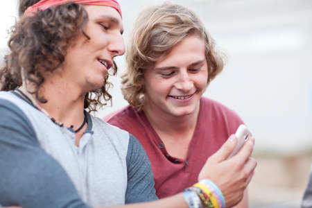 Two young male adult friends looking at smartphone