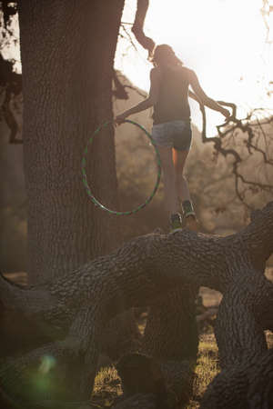 Young woman balancing on fallen tree with hoola hoop, Malibu Creek State Park, California, USA