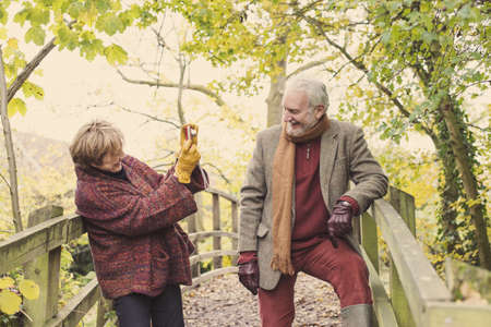 Mature woman photographing senior man