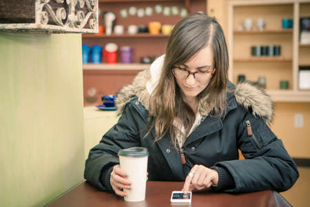 Mid adult woman texting on smartphone in cafe