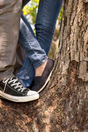Legs and feet of young couple standing on tree