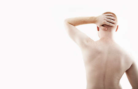 Rear view studio portrait of young man with bare back and hand on his head