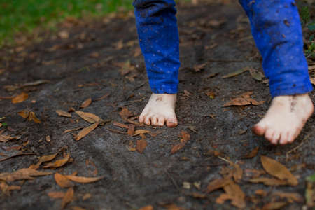 Muddy feet of four year old girl standing in garden soilの写真素材