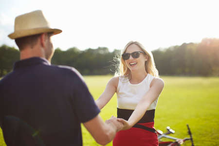 Couple holding hands and swirling each other around in parkの写真素材