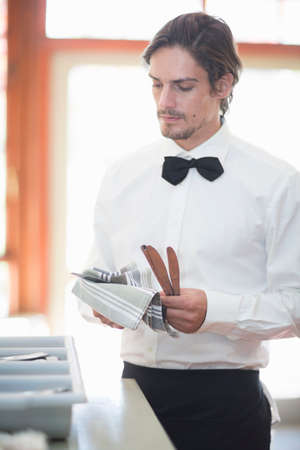 Waiter polishing cutlery in restaurantの写真素材
