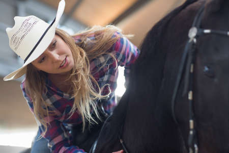 Young woman horseback rider in indoor paddock