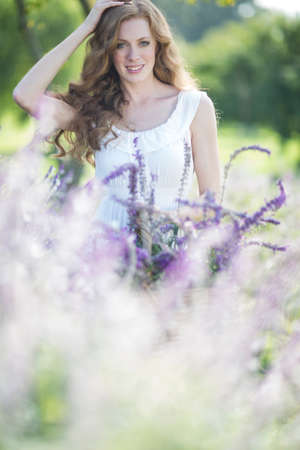Portrait of beautiful young woman in meadow of purple flowersの写真素材