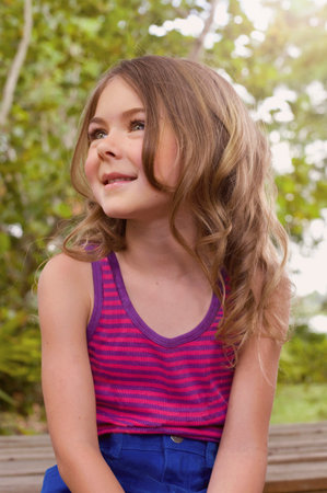 Candid portrait of girl sitting in garden looking away