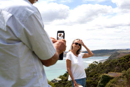 Husband photographing wife, ocean in background, Raglan, New Zealand