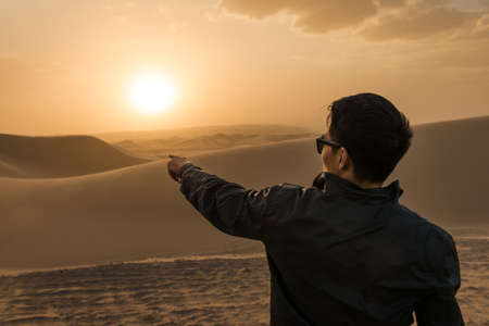 Man pointing into distance, Glamis sand dunes, California, USAの写真素材