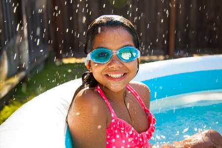 Portrait of girl in swimming goggles in garden paddling poolの写真素材
