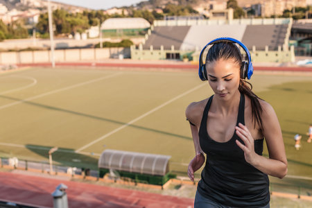 Young woman wearing headphones running, high angleの写真素材