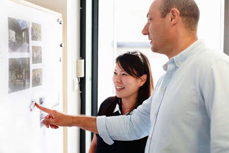 Male and female architects looking at blueprints on office wall