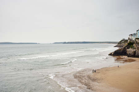 Distant view of people strolling on south beach, Tenby, Walesの写真素材
