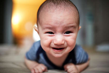 Portrait of baby boy lying on bed with uncertain expression