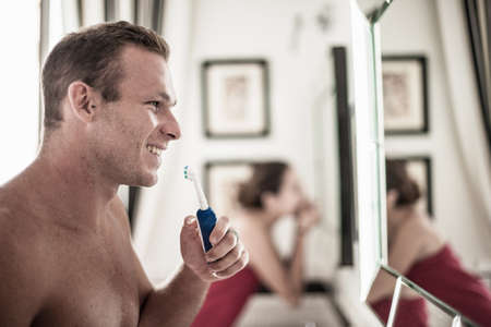 Young couple brushing teeth in his and hers bathroomの写真素材