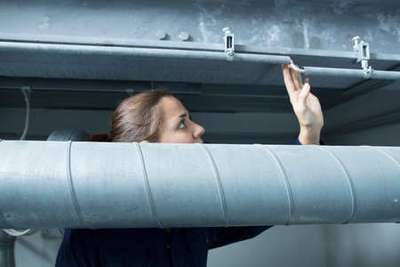 Female engineer looking up at industrial piping in factoryの写真素材