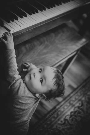 Black and white candid portrait of a baby girl playing pianoの写真素材