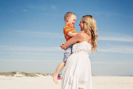 Mid adult mother carrying son on beach, Cape Town, Western Cape, South Africa