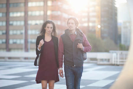 Couple walking across rooftop parking lot in city