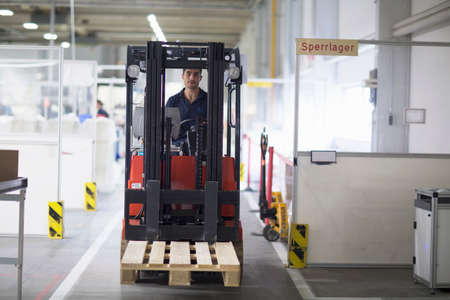 Mature man using forklift truck in factory