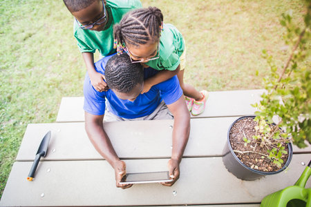 High angle view of father looking at digital tablet with daughter and son at eco camp