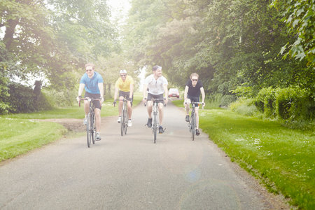 Cyclists riding on leafy countryside road, Cotswolds, UK