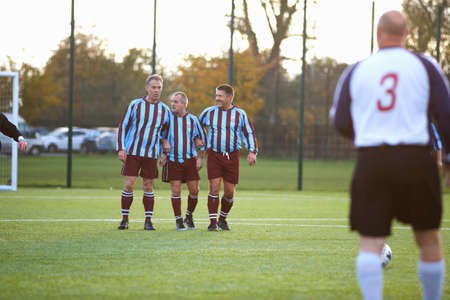 Football players forming wall to defend free kickの写真素材
