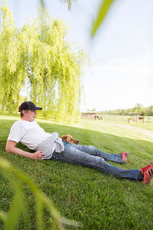Man relaxing on grass with dogの写真素材