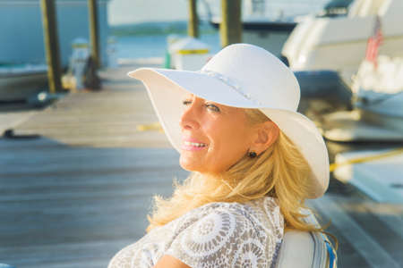 Mature woman sitting on harbor pier, Monmouth Beach, New Jersey, USAの写真素材
