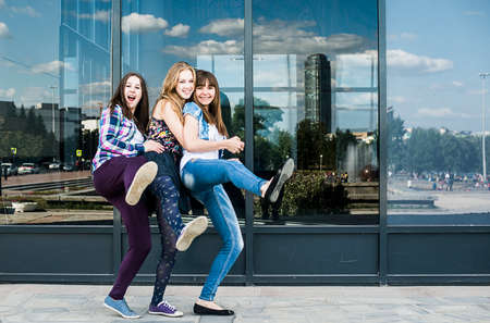 Three young women dancing on one leg in cityの写真素材