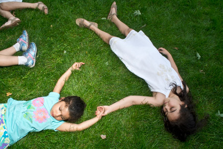 Four girls lying on their backs in park at summer campの写真素材