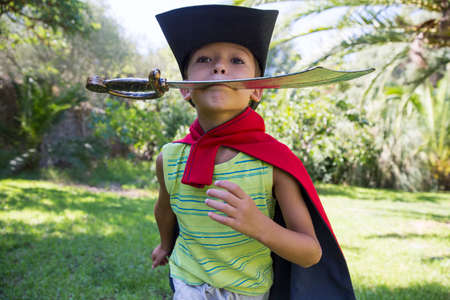 Young boy wearing fancy dress costume, running in park