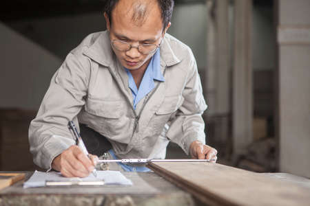 Carpenter measuring wood plank with vernier caliper in factory, Jiangsu, Chinaの写真素材