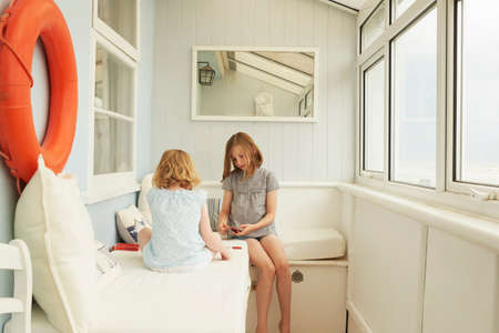 Two sisters playing cards in holiday apartment porchの写真素材