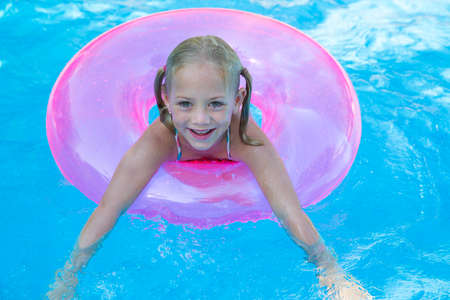 Portrait of girl in inflatable ring in garden swimming poolの写真素材