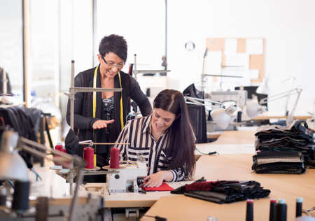 Two seamstresses at sewing machine in workshopの写真素材
