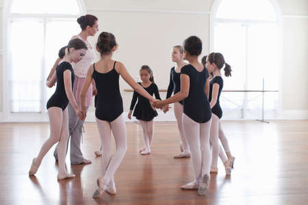 Ballet teacher holding hands with group of ballet school girlsの写真素材