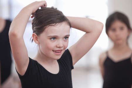 Girl pinning back her hair in ballet schoolの写真素材