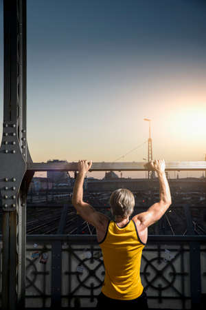 Man doing chin-ups on bridge, Munich, Bavaria, Germanyの写真素材