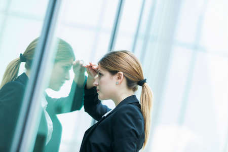 Businesswoman peering through glass windowの写真素材