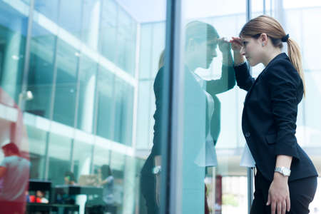 Businesswoman peering through glass windowの写真素材