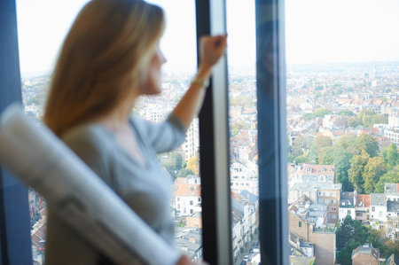 Female architect gazing from office window at Brussels cityscape, Belgium
