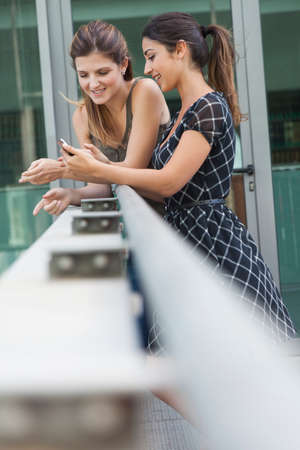 Women using phone outside the libraryの写真素材