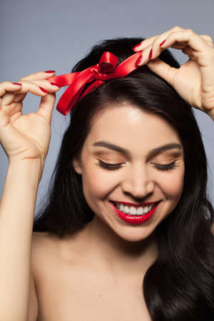 Mid adult woman tying red ribbon in hairの写真素材