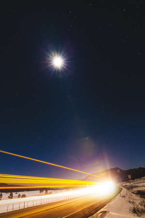 Highway light trails and full moon at night, Pagosa Springs, Colorado, USAの写真素材