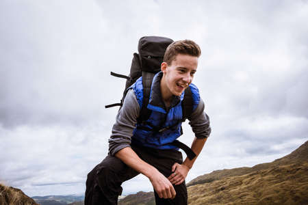 Young male hiker reaching top of mountain, The Lake District, Cumbria, UK