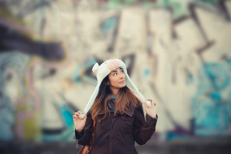 Portrait of mid adult woman wearing fur hat in front of graffiti wallの写真素材